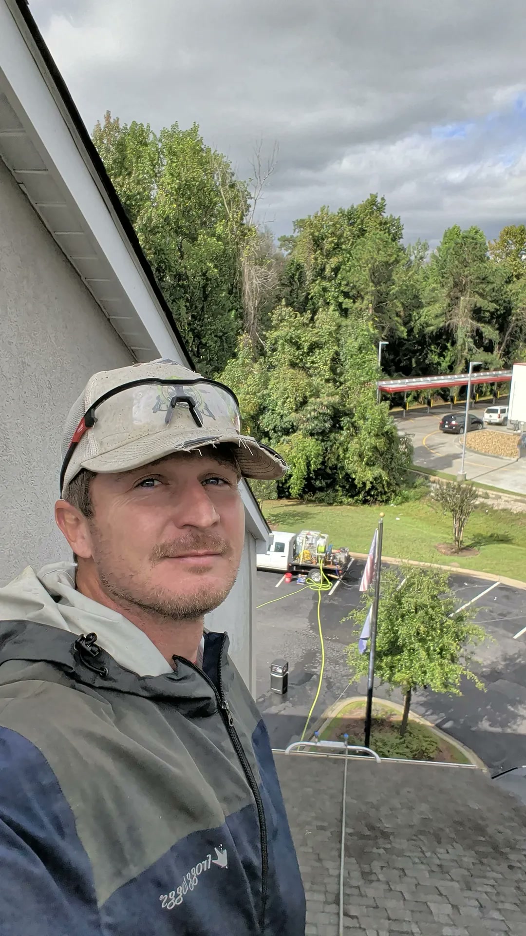 Jeremy on a roof, mid job, the truck and hose in the lot below